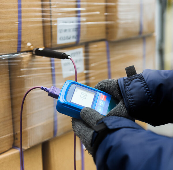 Hand of worker using thermometer to temperature measurement in the goods boxes with ready meals after import in the cold room or warehouse for keep temperature room